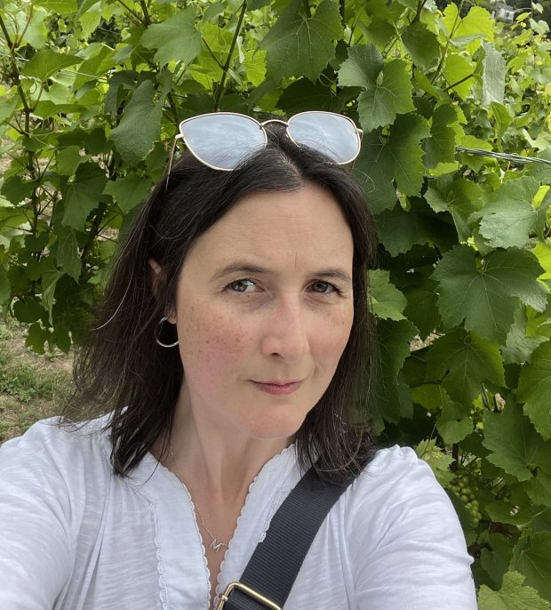 Marie Kaiser Wine Translator standing in front of vines in a UK vineyard
